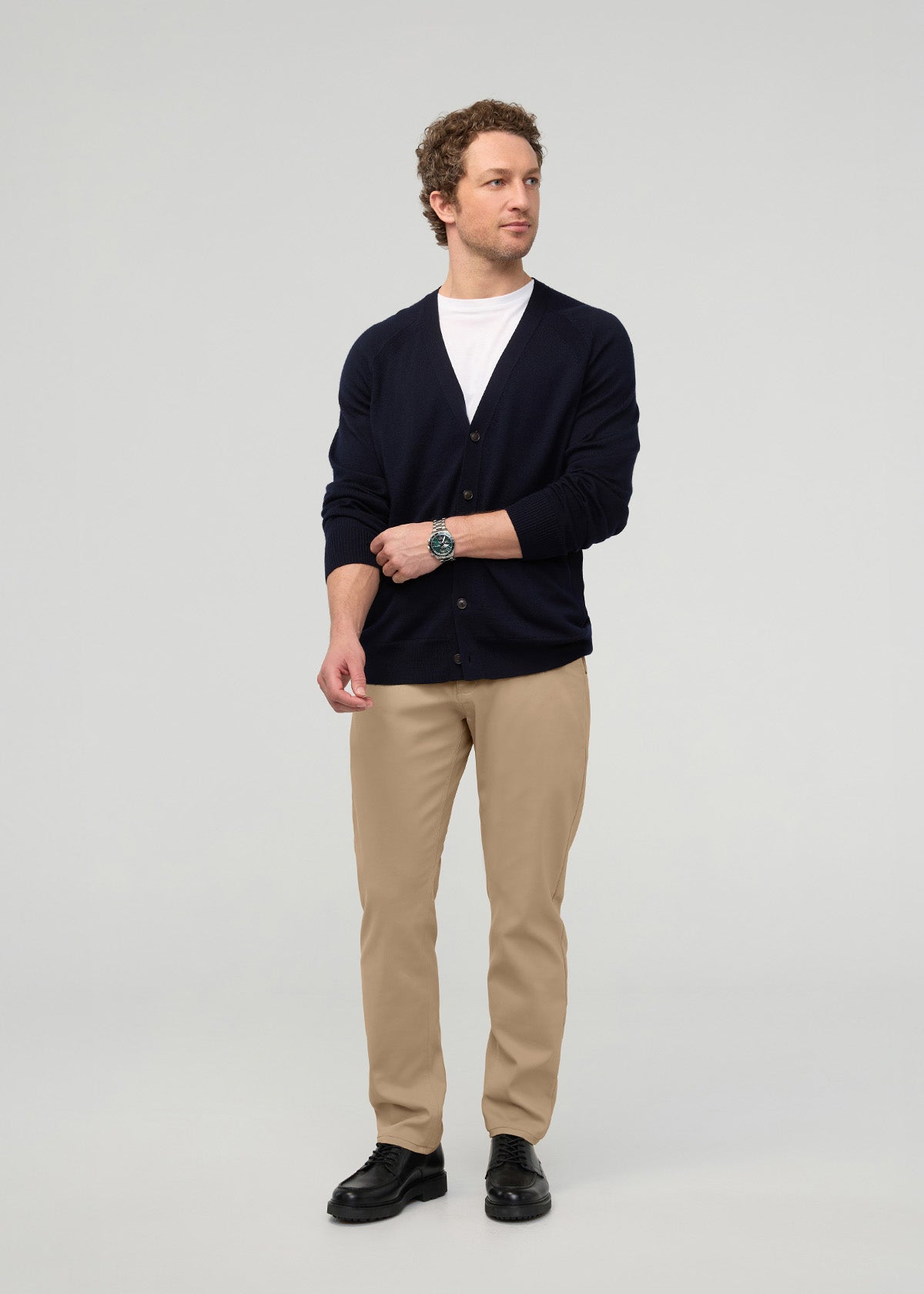 Man wearing desert khaki relaxed taper trousers with navy cardigan and white t-shirt.