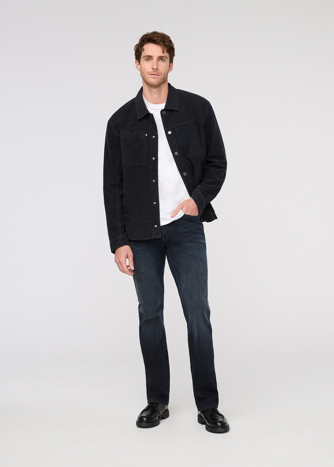 Man wearing a black jacket, white shirt, and dark jeans on a white background