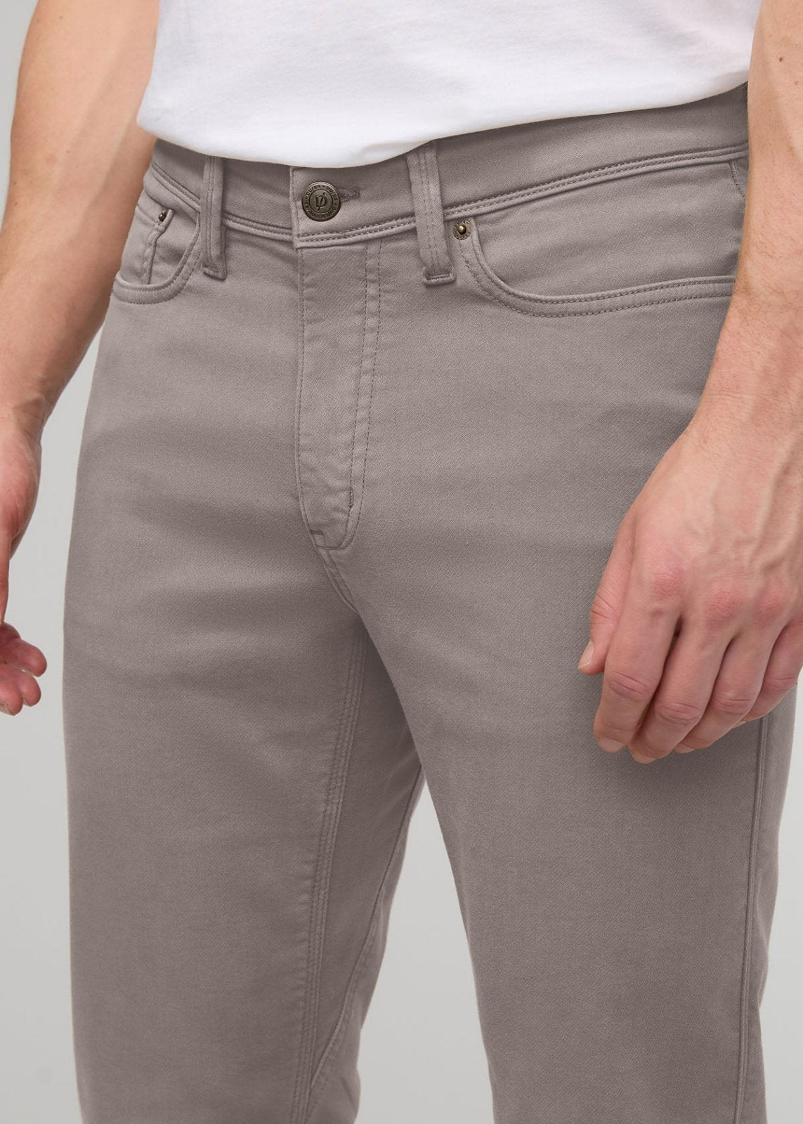 Stone-colored straight-leg pants with button and zip closure, worn with white t-shirt.