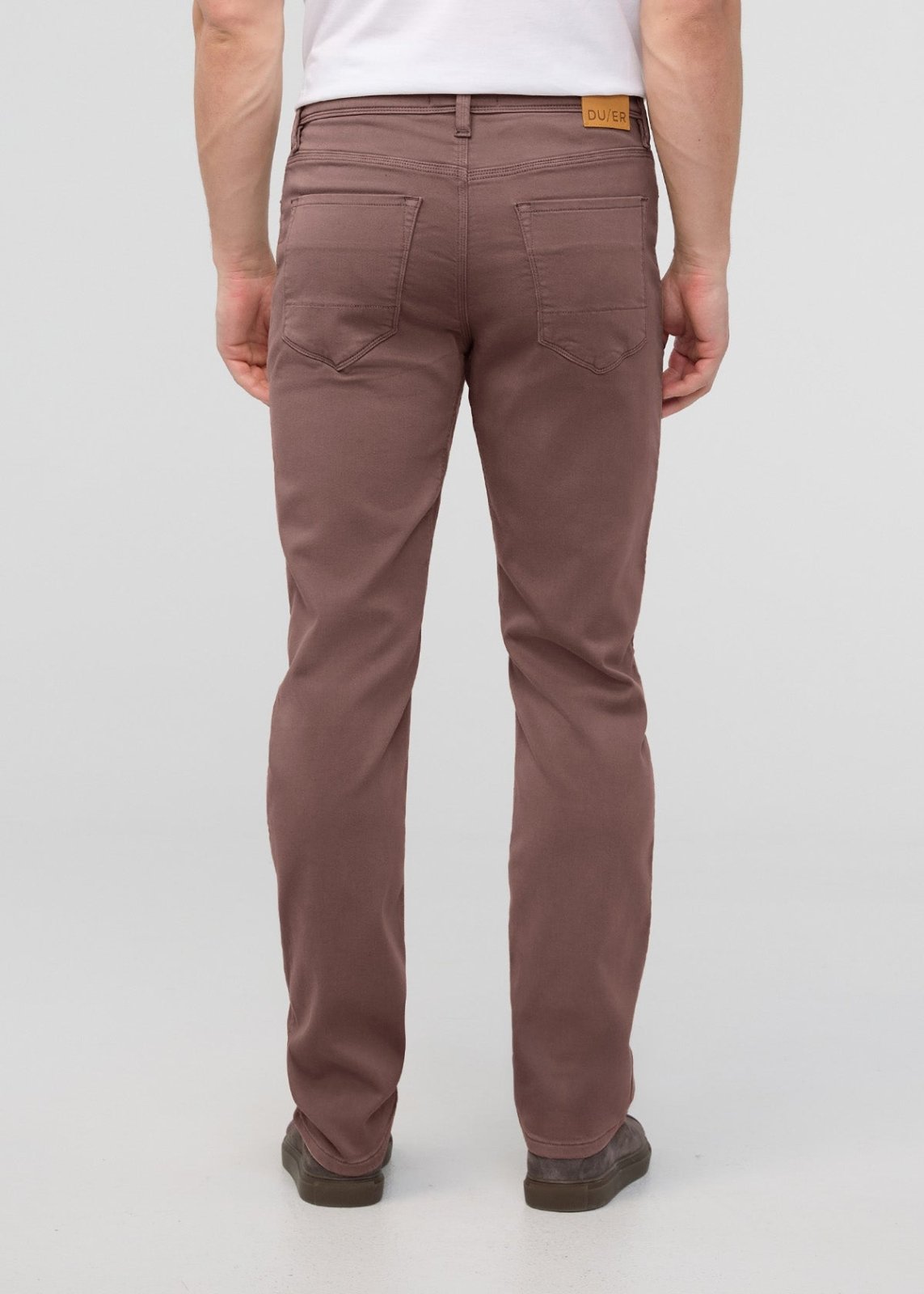 Man wearing mauve straight-leg pants with back pockets and brown leather belt label, shown from behind.