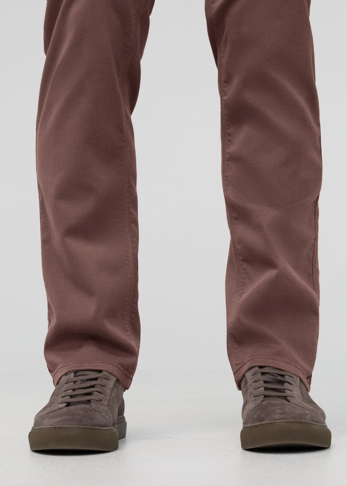 Brown straight-leg pants paired with gray suede lace-up sneakers with tan soles.