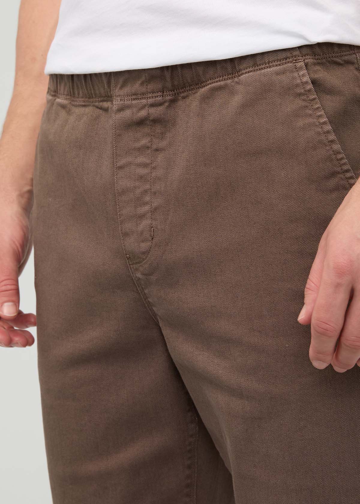 Tan relaxed pull-on pants with elastic waistband on model wearing white shirt.