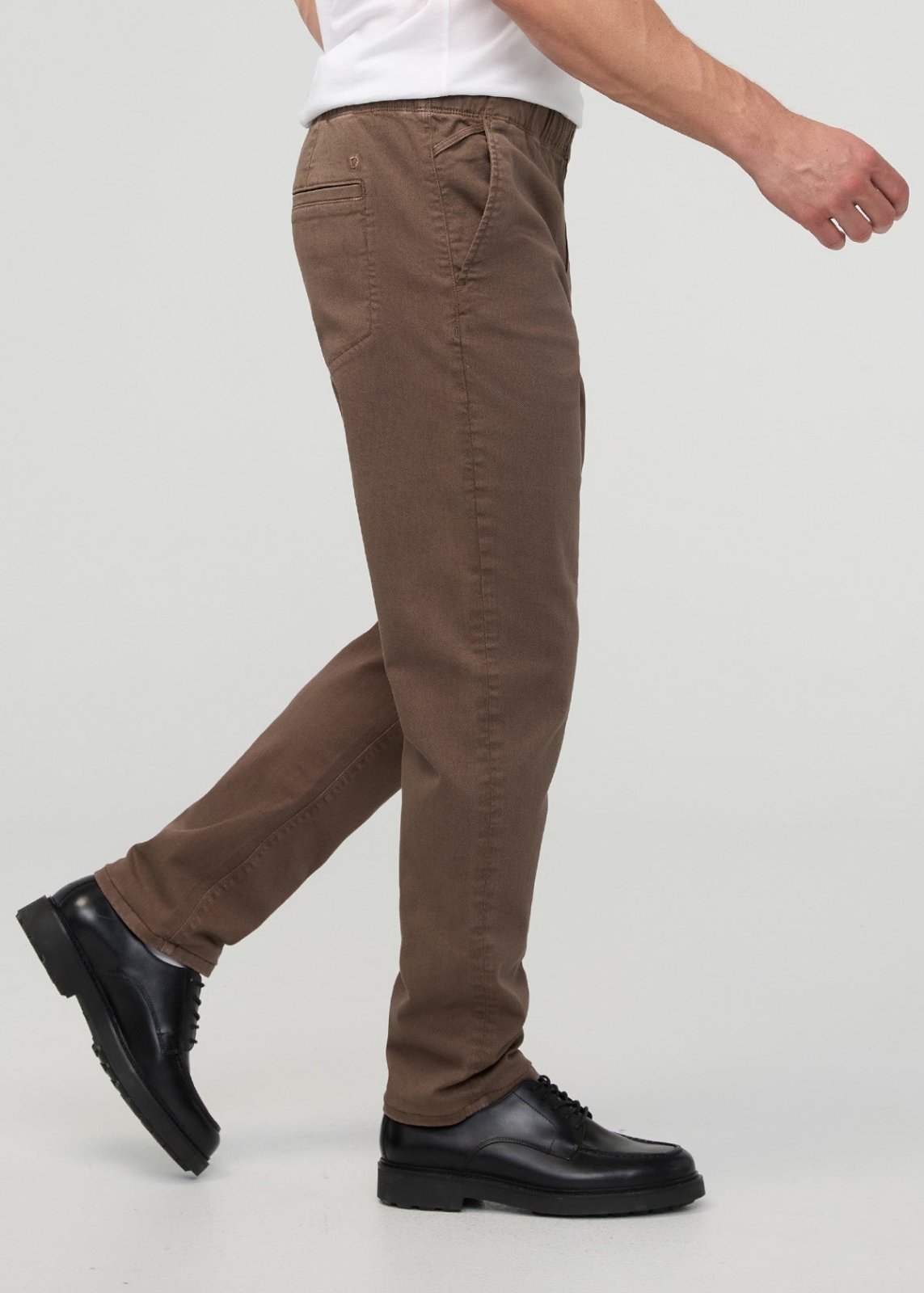 Tan relaxed pull-on pant with elastic waistband worn with white shirt and black lace-up shoes.