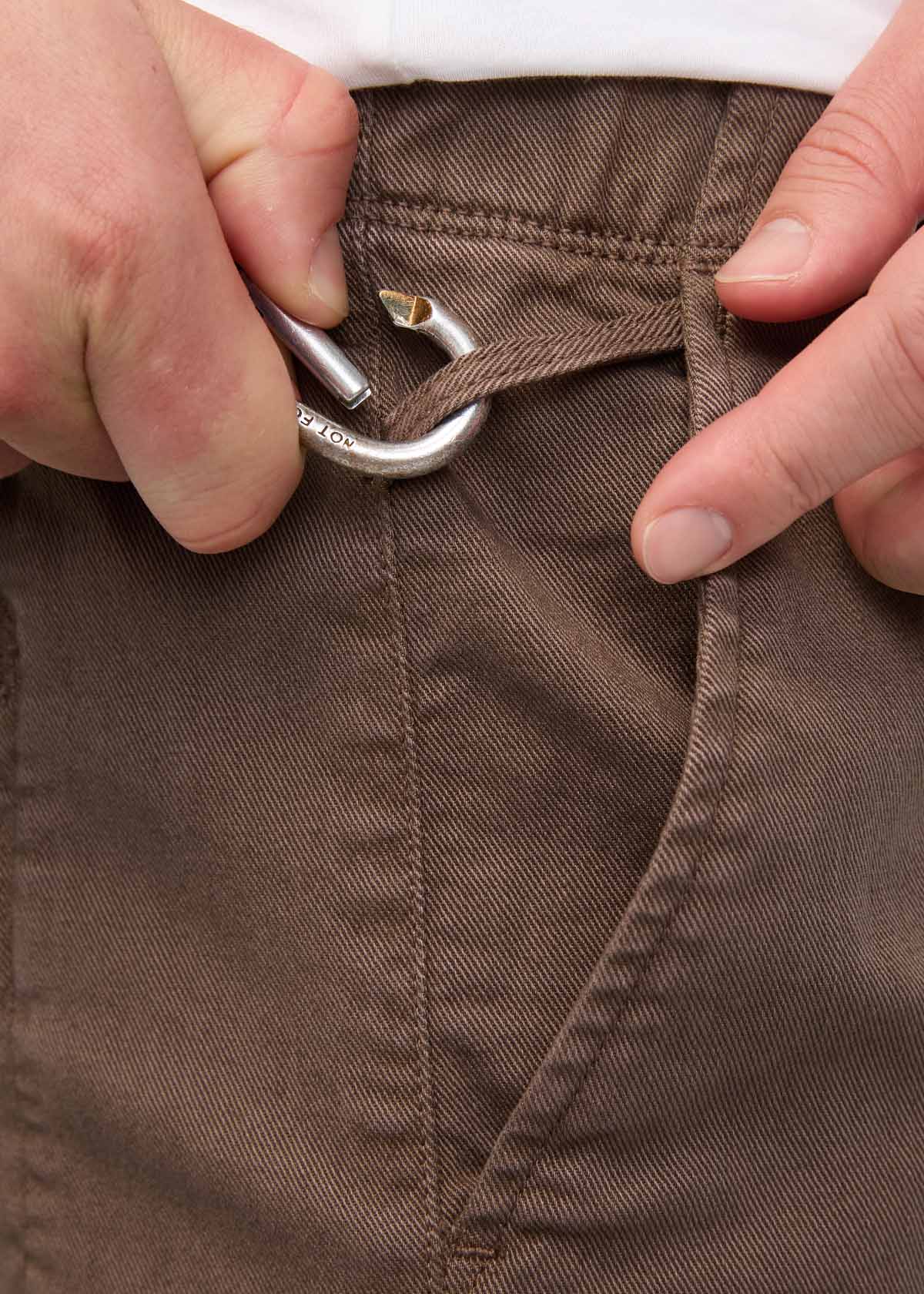 Close-up of canteen-colored pants waistband with metal drawstring hook and elastic pull-on closure.