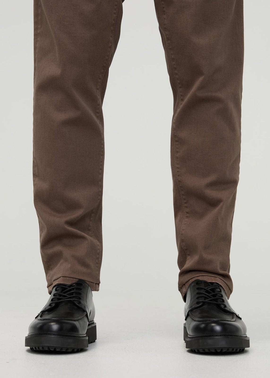Brown relaxed pull-on pants in twill fabric paired with black lace-up shoes with platform sole.