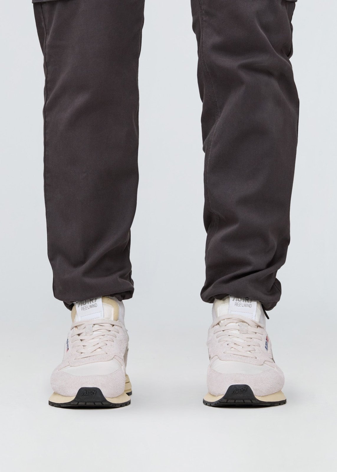 Charcoal relaxed-fit pants with straight leg shown on model wearing white sneakers.