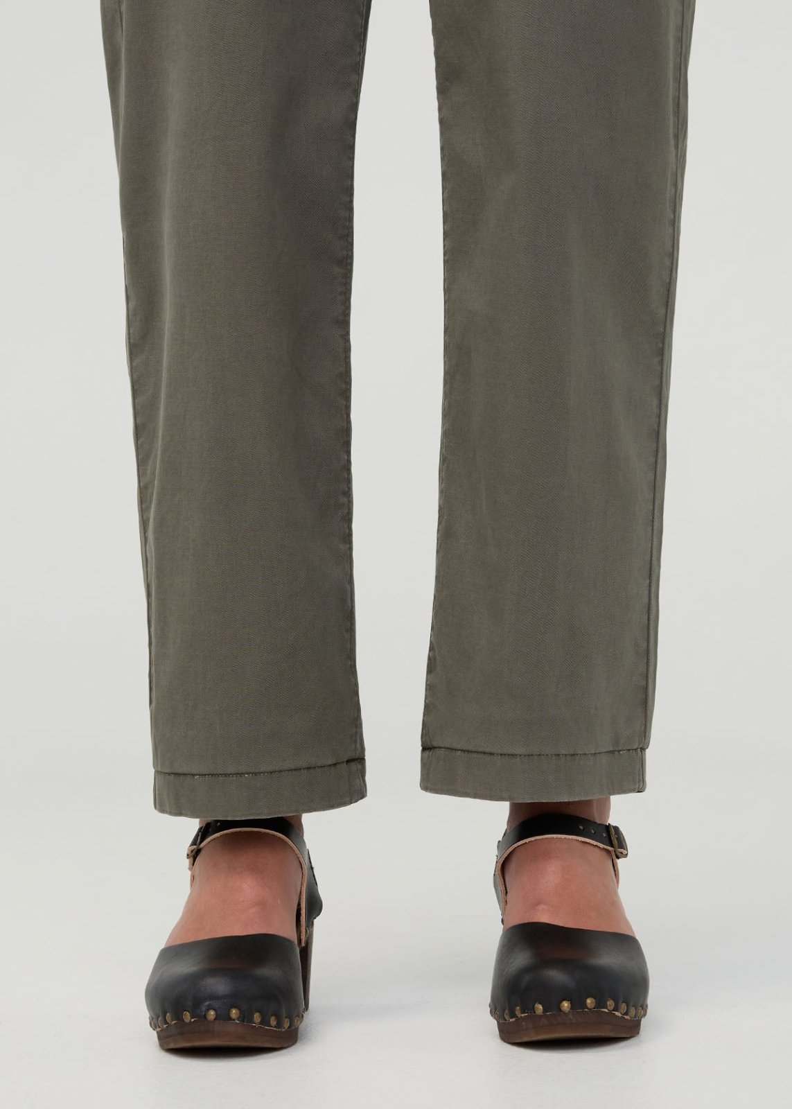 Thyme-colored boiler suit pants with cuffed hems, shown on model wearing black studded clogs.