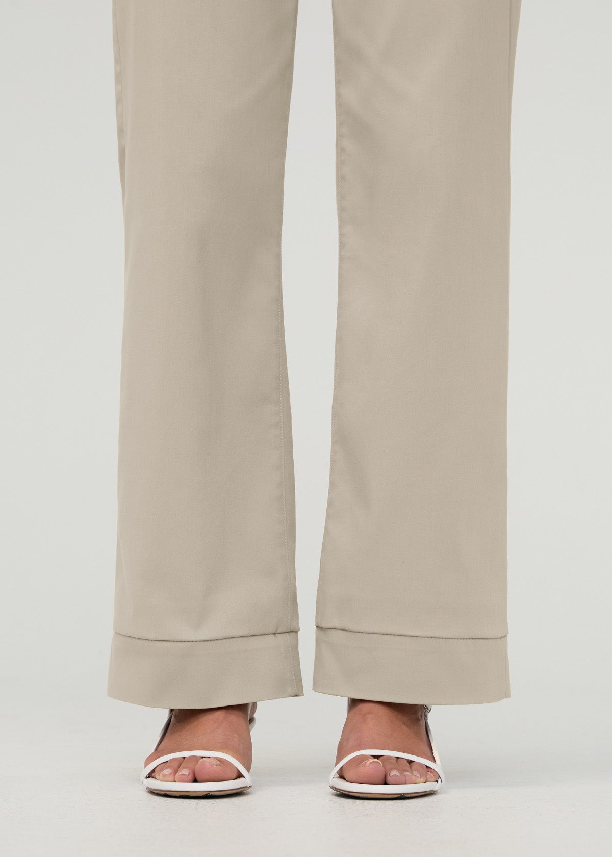 Sandstone high-rise trousers with hem cuff detail, shown with white slide sandals.