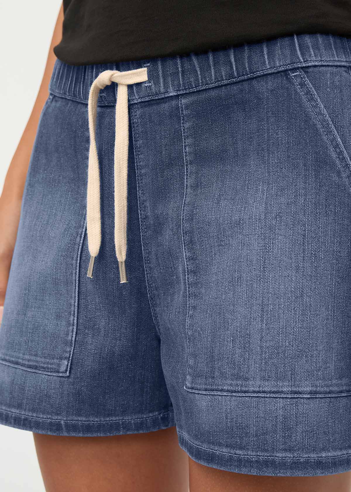 Blue denim shorts with drawstring waist and patch pockets, paired with black t-shirt.