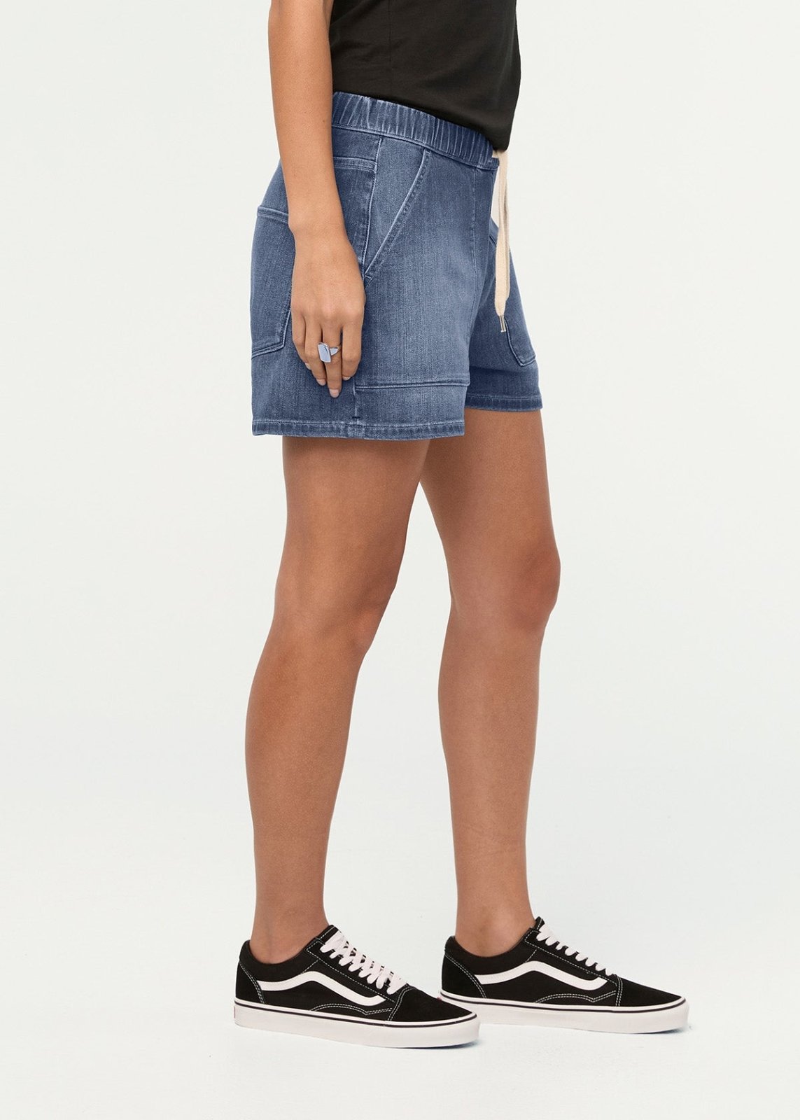 Blue denim shorts with elastic waistband and front pockets, paired with black and white sneakers.
