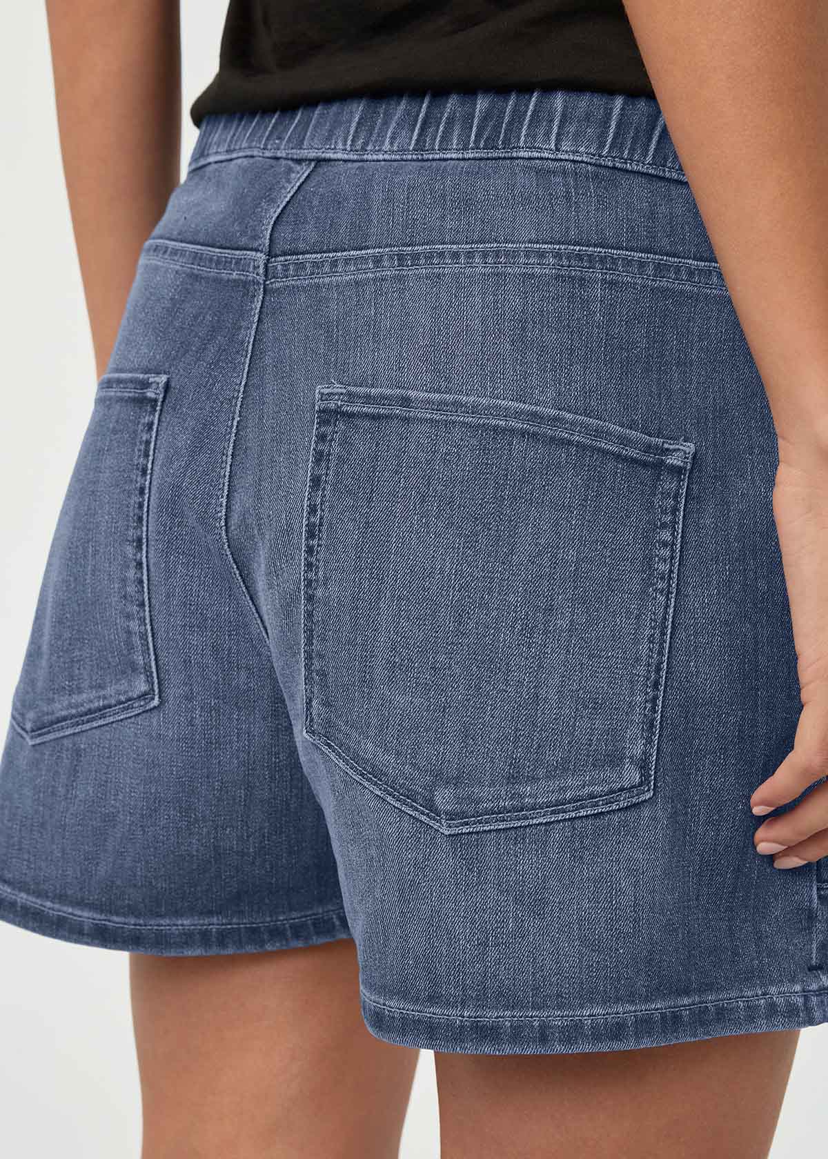 Blue denim shorts with elasticated waistband and rear pockets, worn with black top.