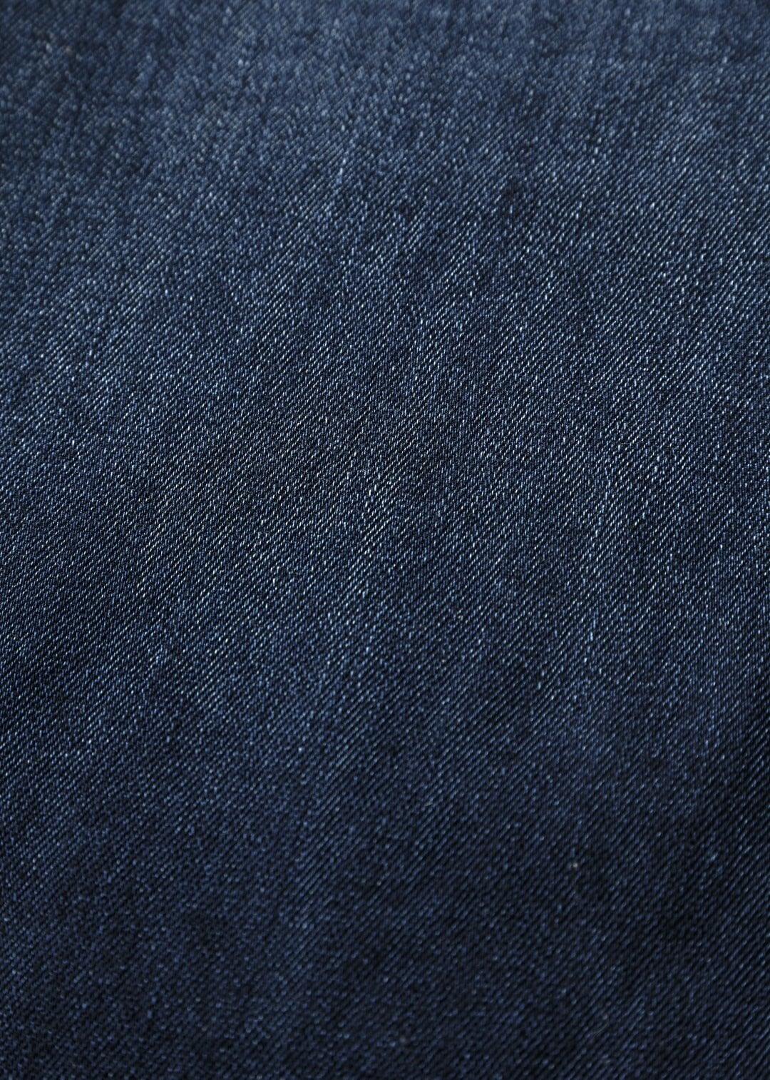 Dark stone denim fabric with diagonal weave texture and subtle white flecks throughout.